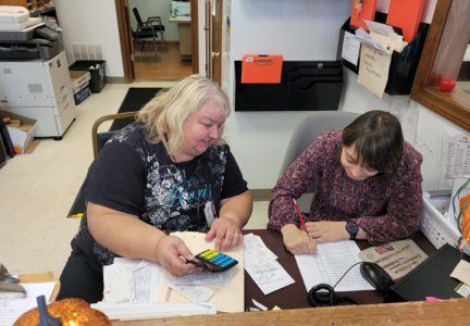 Two people at a desk filling out forms