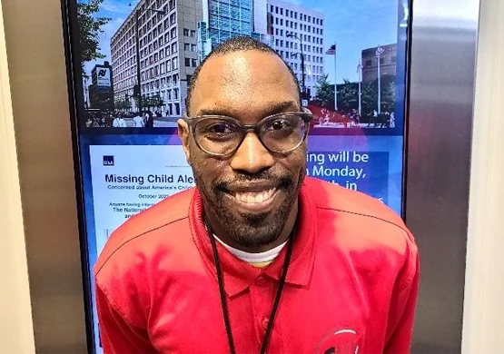Worker in a lanyard standing in front of a sign