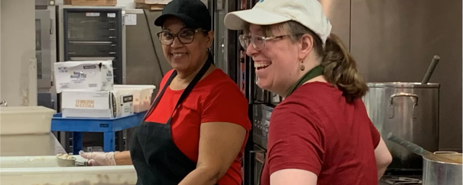 Two workers wearing aprons in an industrial kitchen