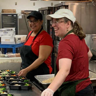 Two people prepping meals in an industrial kitchen