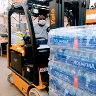 Person using a forklift to move pallets of bottled water