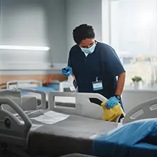 Person sanitizing the rails of a hospital bed