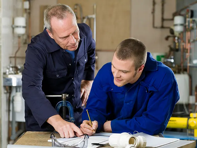 Two people in a tech shop, one is helping the other with paperwork