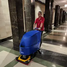 Person pushing floor cleaning machine over a tiled lobby floor