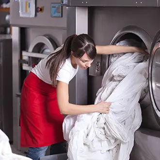 Person taking laundry out of an industrial washing machine