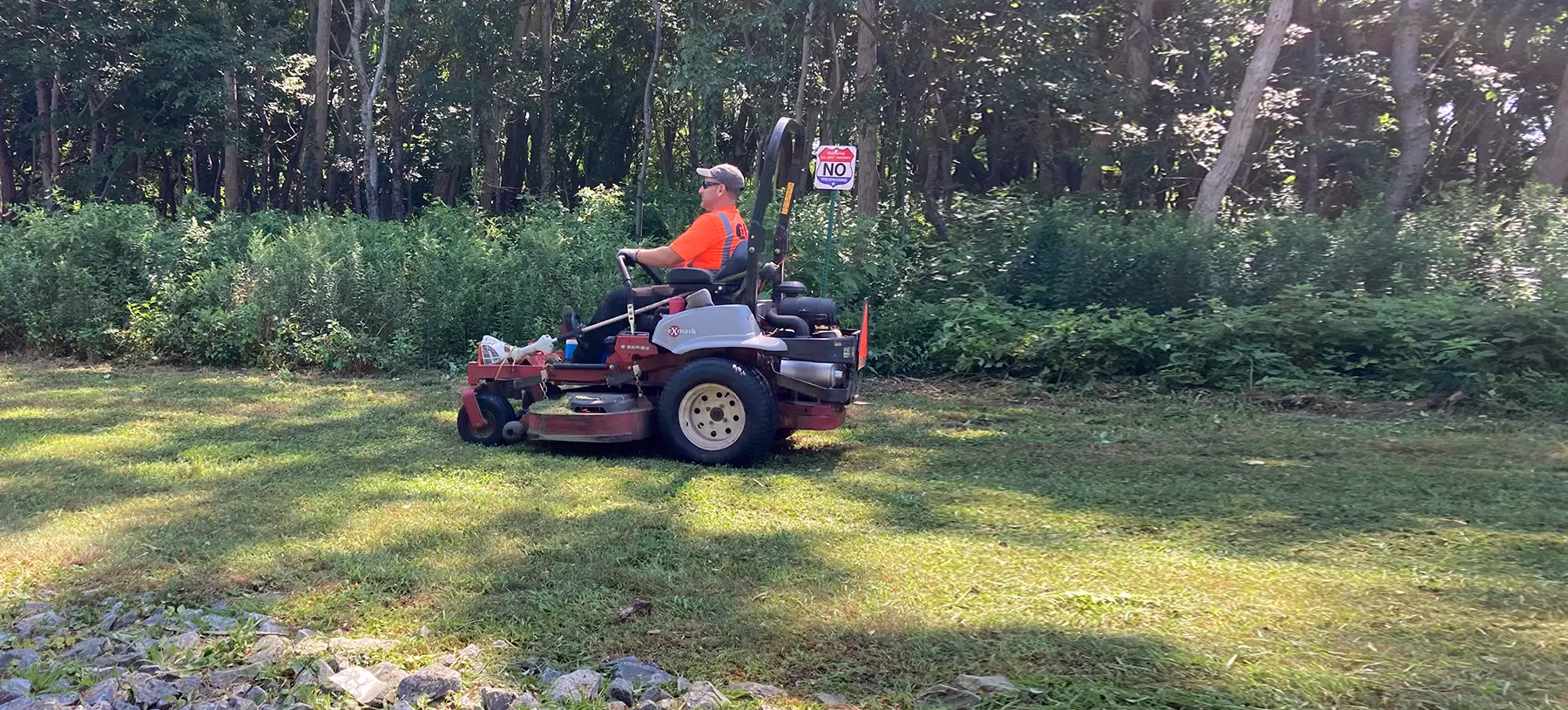 Person driving riding lawn mower over grass
